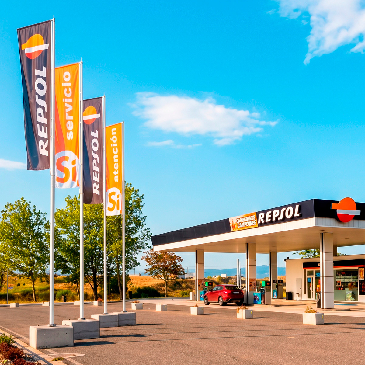 Mástiles VDK con banderas Repsol en estación de servicio